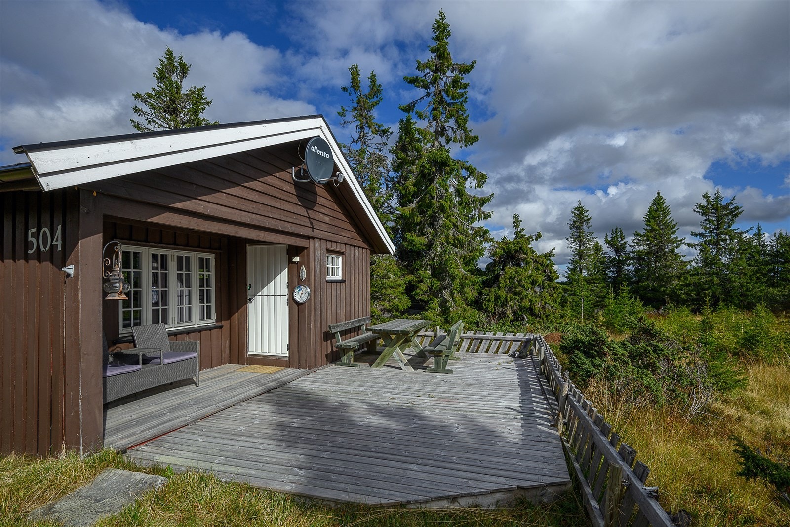 Romslig terrasse med et lite overbygg ved inngangen av hytta. Galleribilde