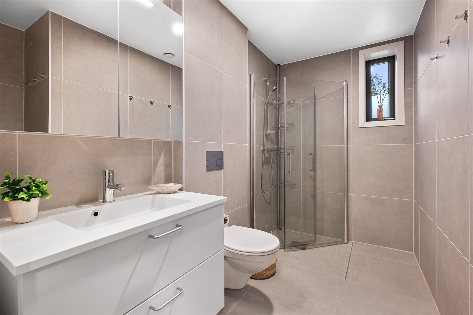 Lekkert flislagt bad med dusjnisje, vegghengt wc og pen baderomsinnredning Galleribilde