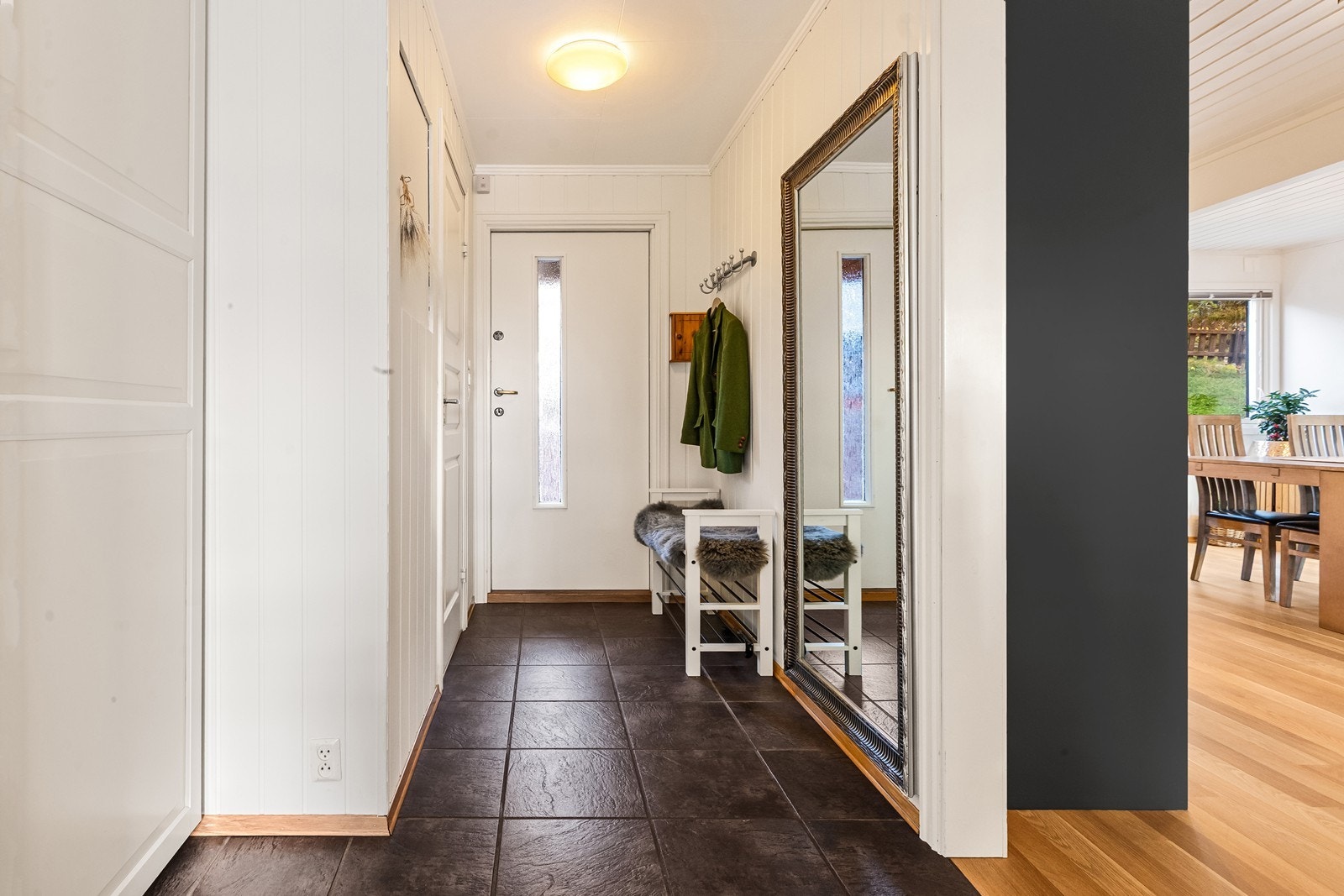 Hyggelig entré med flislagt gulv og panelte overflater. Galleribilde