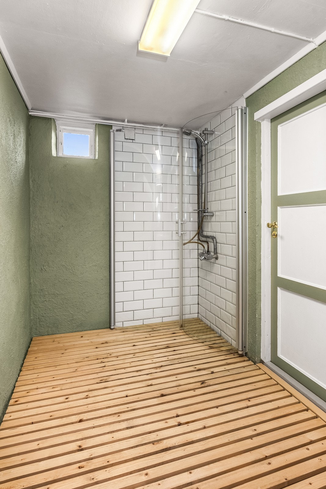 Dusjnisje med innfellbare glassdører, flislagte vegger og gulv av tre. Servantinnredning og speil. Galleribilde