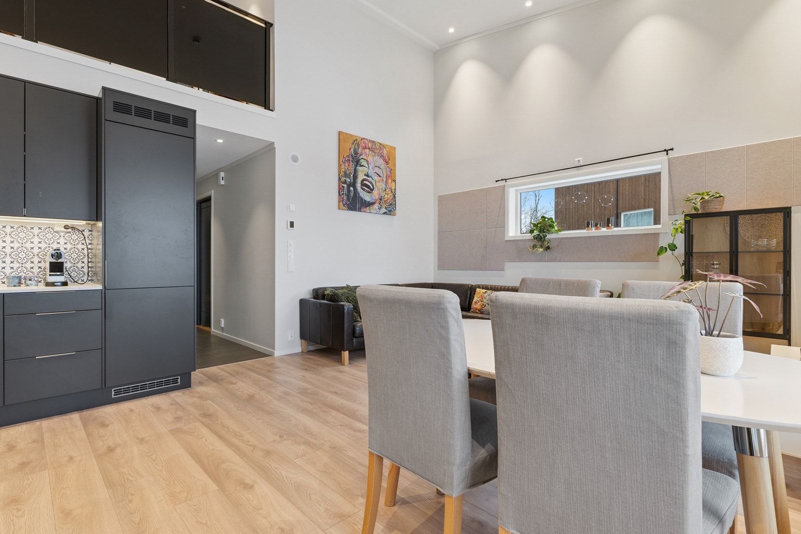 Loftstuen er åpen ned mot stuen, avgrenset av et stilrent rekkverk i glass. Galleribilde