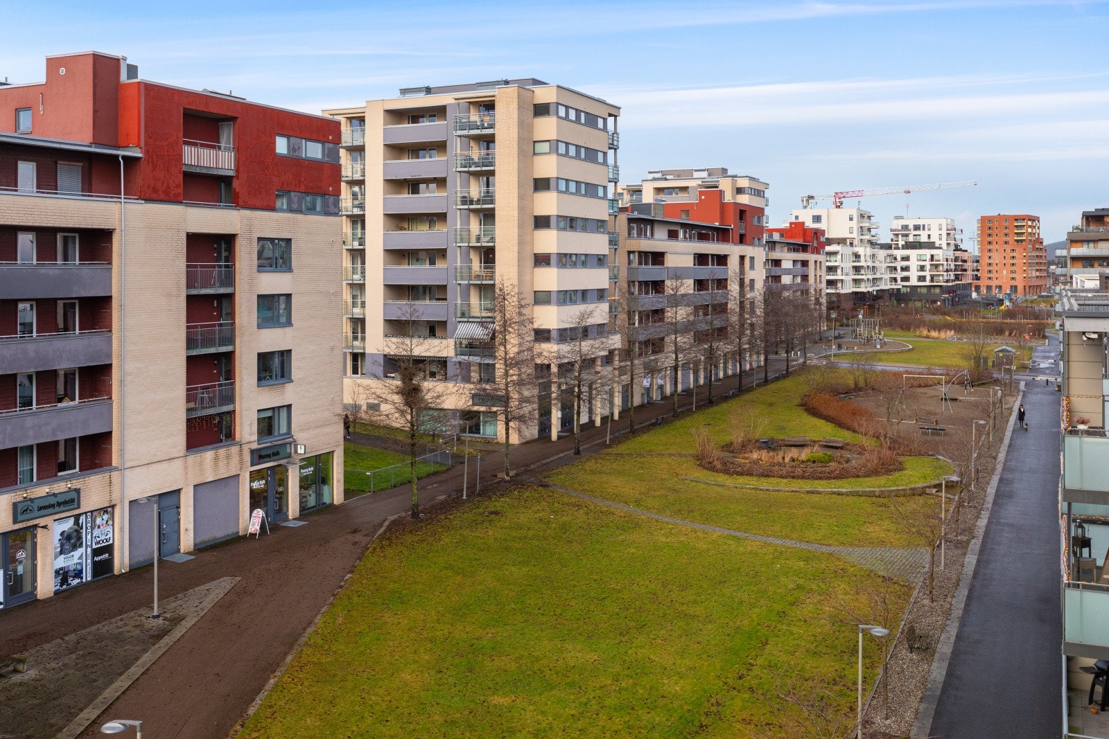 Leiligheten ligger i et område med moderne boligbygg, omgitt av grøntarealer og gangveier. Galleribilde