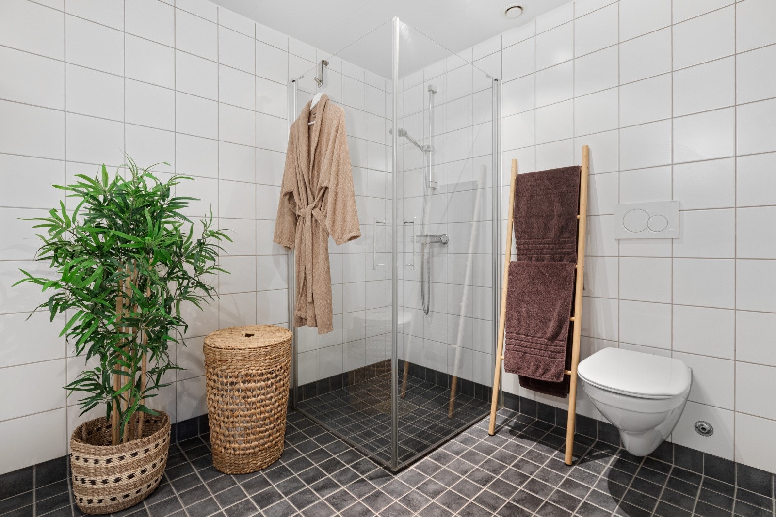 Badet er utstyrt med vegghengt toalett, dusjhjørne og baderomsinnredning. Galleribilde