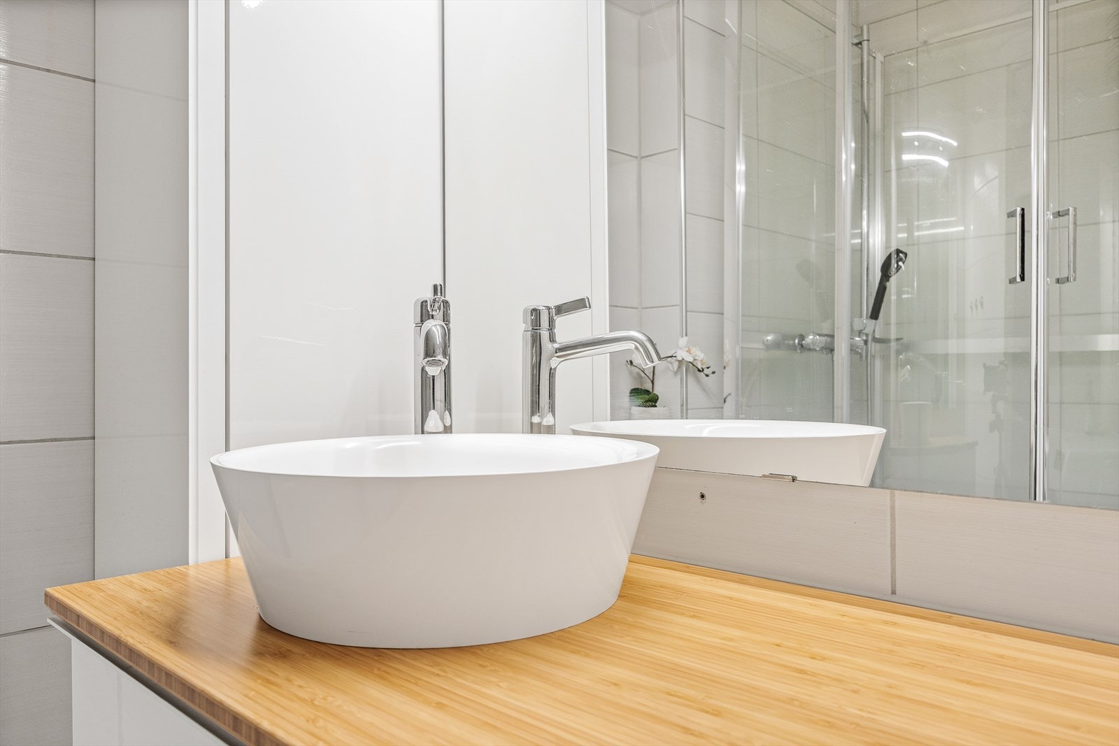 Badet er utstyrt med dusjkabinett og servantinnredning med skuffer og sideskap Galleribilde