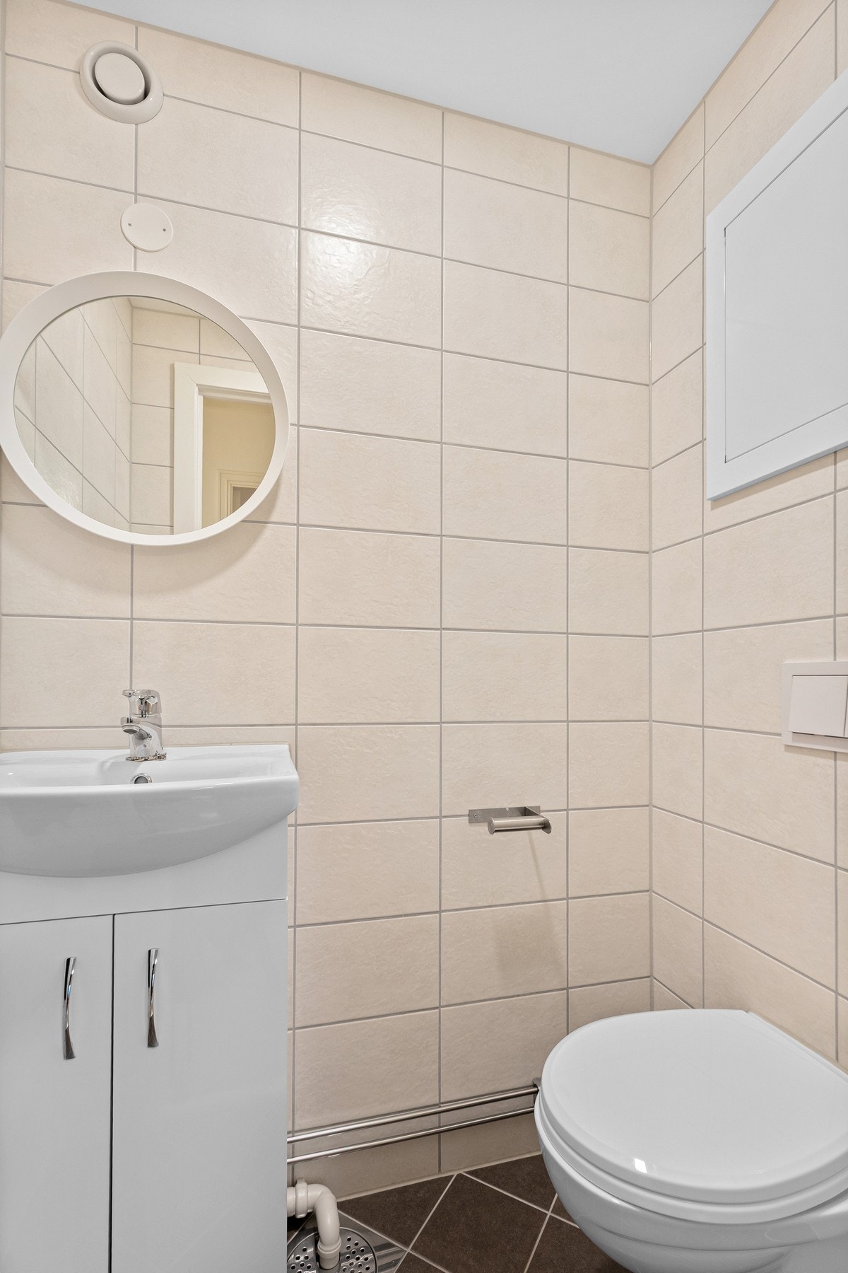 Separat toalettrom med fliser på gulv og vegger og slett hvitmalt tak. Rommet er utstyrt med wc og servant, og har en funksjonell og ryddig utforming som er praktisk i hverdagen. Galleribilde