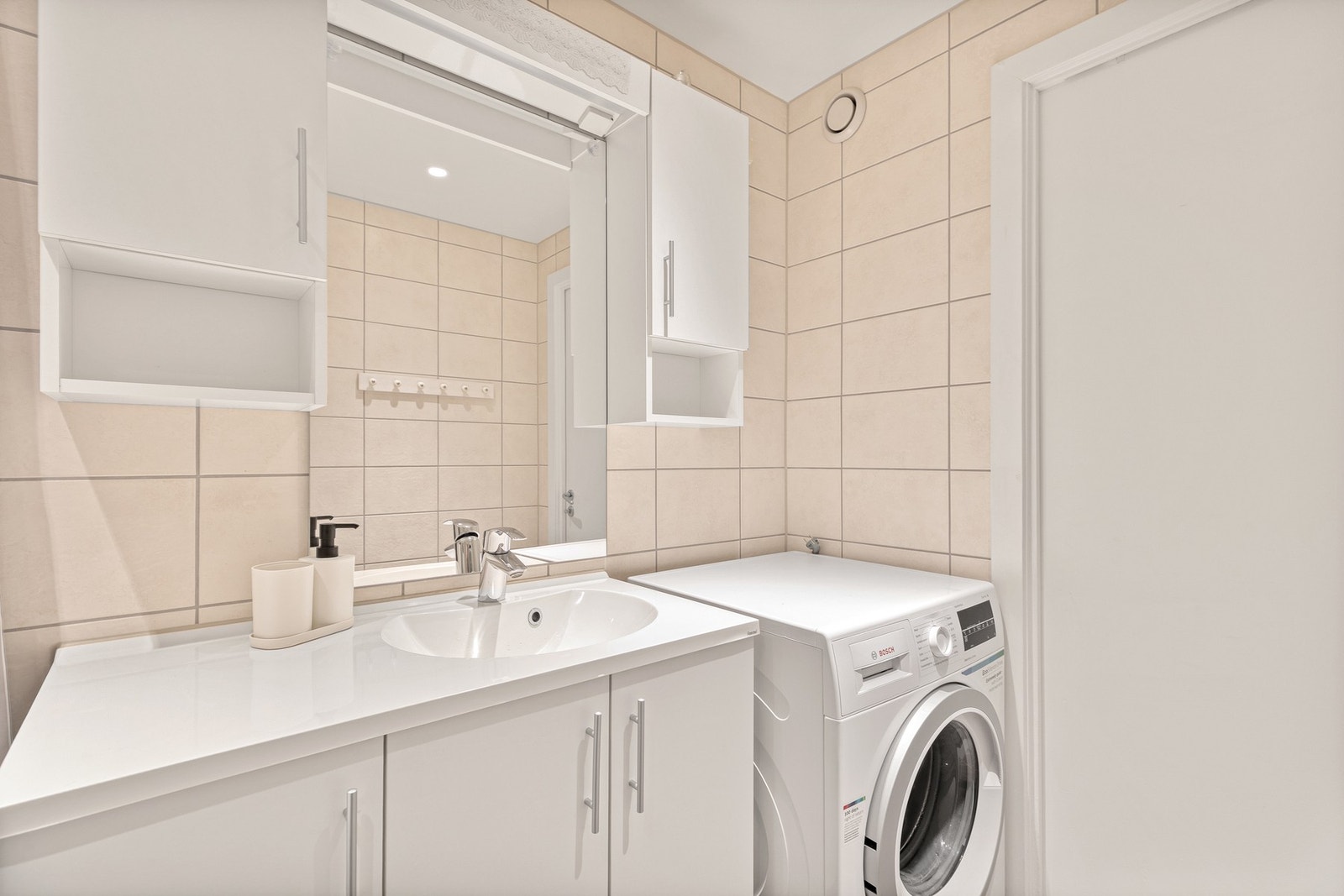 Badet har fliser på gulv og vegger, hvitmalt slett tak med downlights og varmekabler i gulv som gir god komfort. Galleribilde