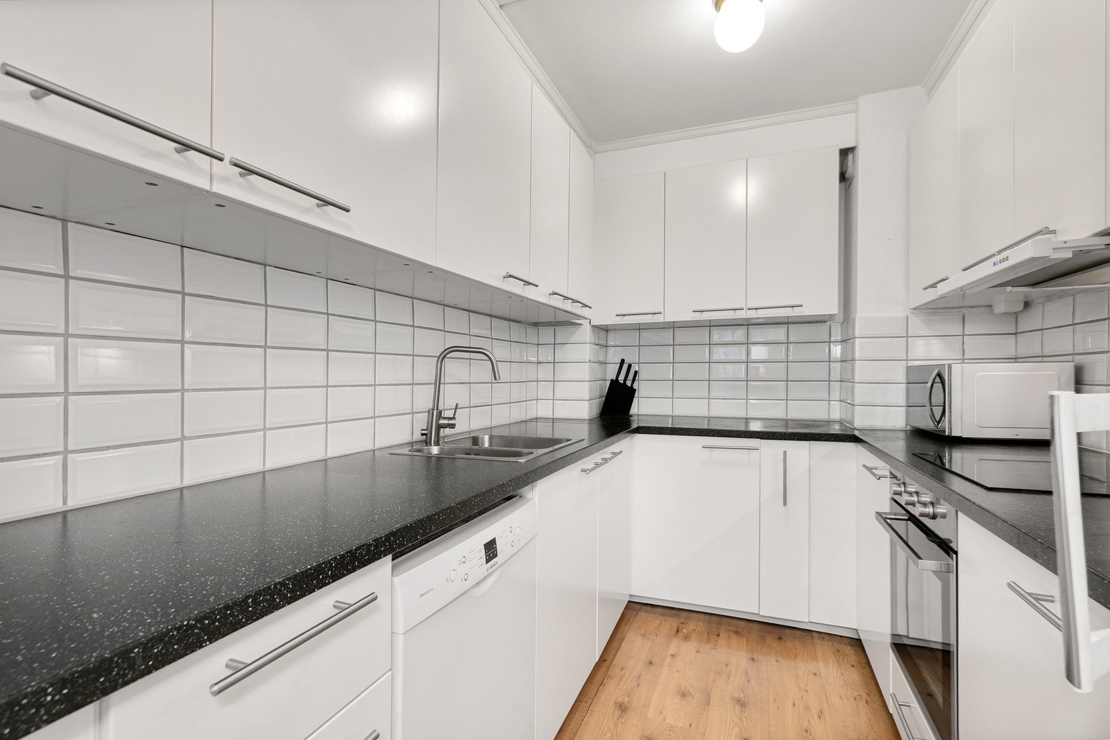 Kjøkken fra 2018 med innredning i glatte fronter som gir et stilrent og tidløst uttrykk. Praktisk benkeplate i laminat med fliser på vegger over benkeplate. Galleribilde