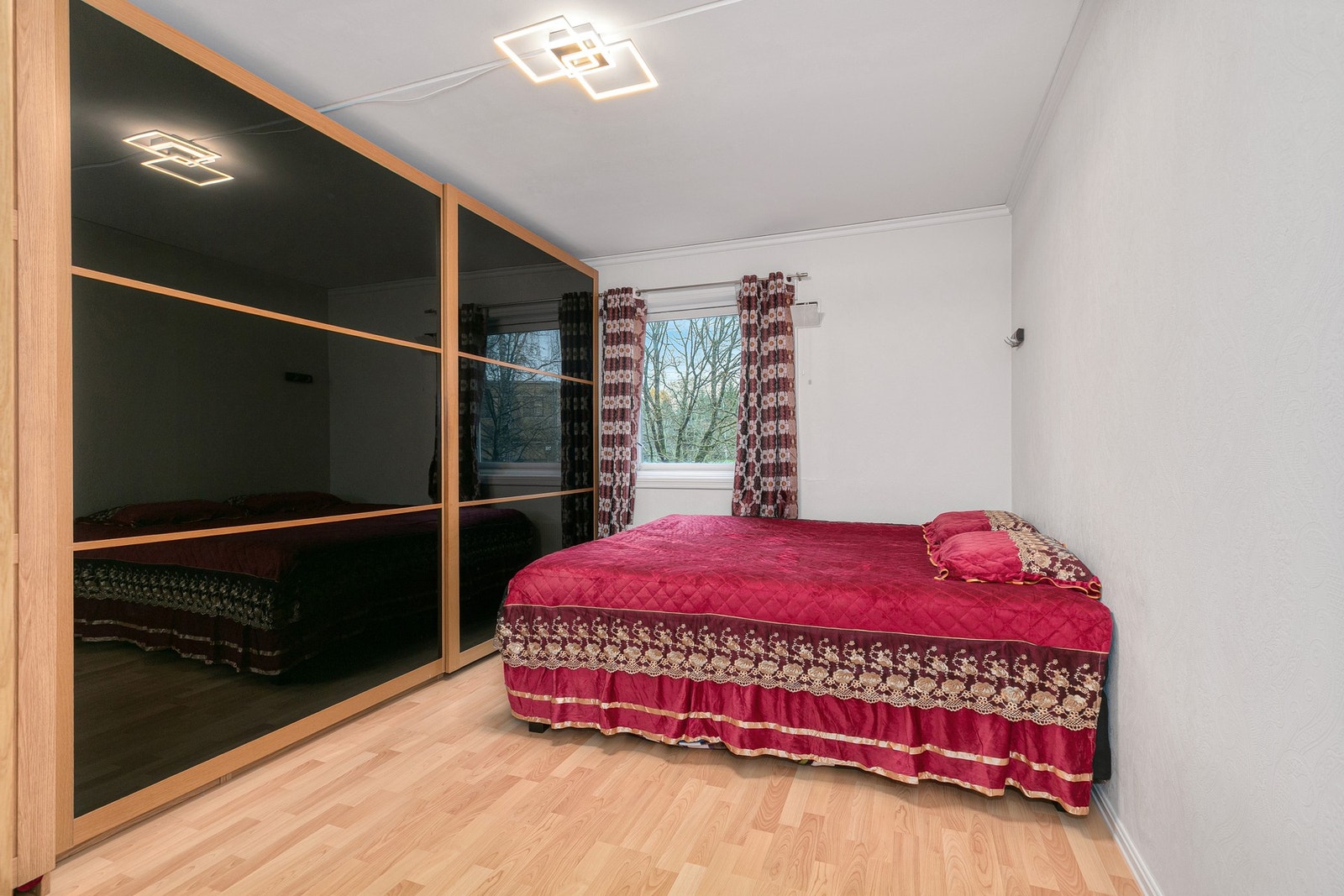 Romslig hovedsoverom med lyse overflater og stort vindu som gir godt med naturlig lys. Galleribilde