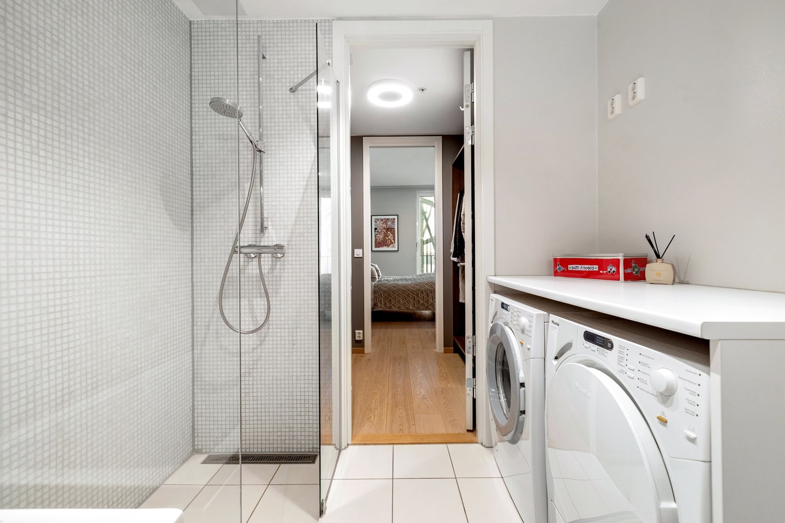 Leiligheten har et meget delikat baderom, pent flislagt med med lyse gulv- og veggfliser. Badet har en fin størrelse og er innredet med dusjnisje og badekar, samt benkeplate med opplegg for både vaskemaskin og tørketrommel. Galleribilde