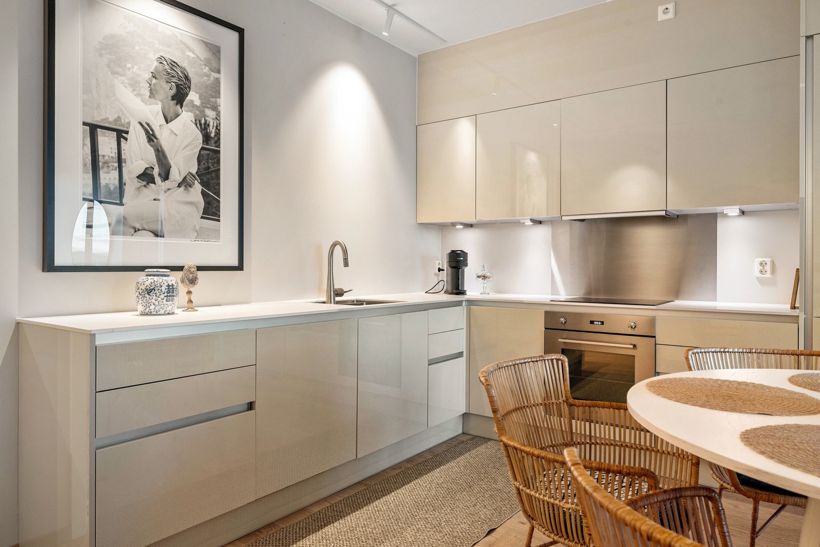 Kjøkkenet ligger i åpen løsning mot stuen og har en moderne innredning med lyse, slette fronter og laminatbenkeplate Galleribilde