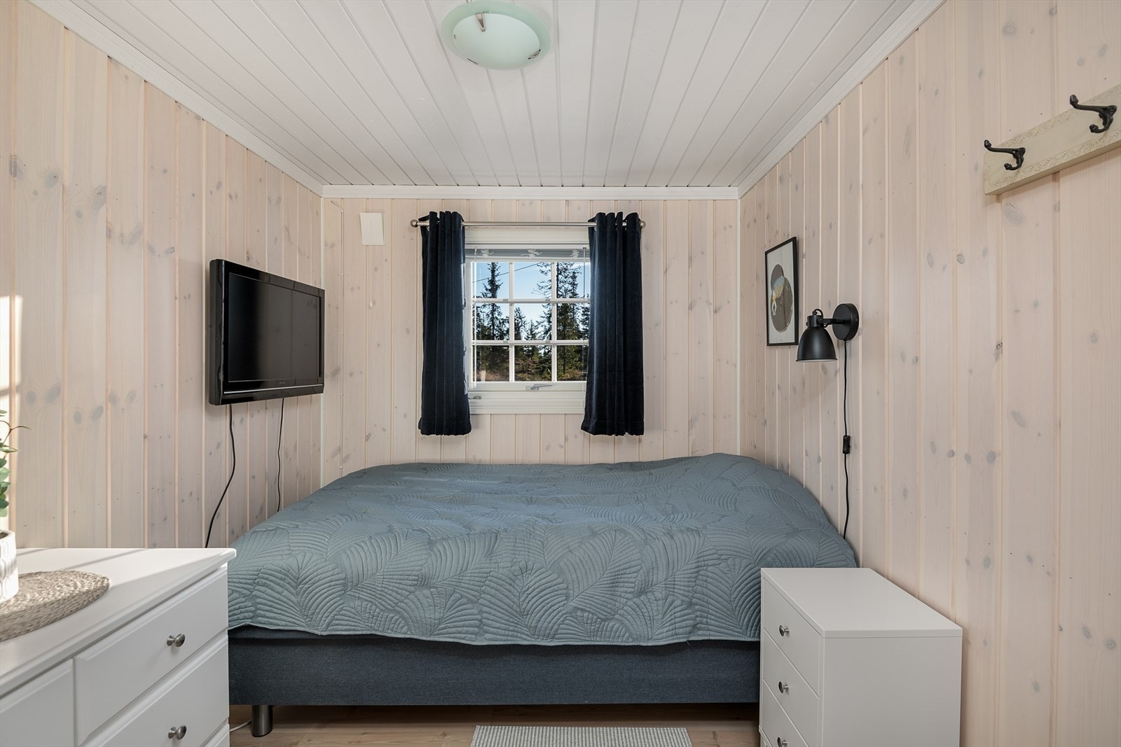 Soverom 3 er innredet med dobbeltseng og kommode for oppbevaring av klær. Her er veggene kledd med hvitpigmentert panel. Galleribilde