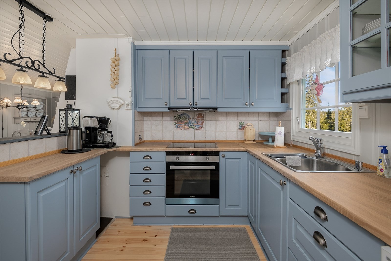 Innredningen har profilerte fronter, malt i en dus og innbydende blåtone. Det er godt med oppbevaringsplass på kjøkkenet. Galleribilde