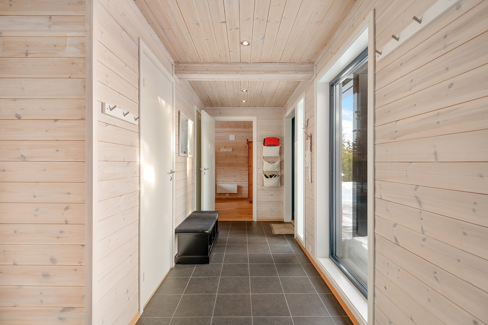 Romslig, flislagt gang i hytta med plass til å henge fra seg yttertøy og utstyr. Fra gangen er det direkte adkomst til 2 av soverommene og wc, samt dør inn til oppholdsrommet. Galleribilde
