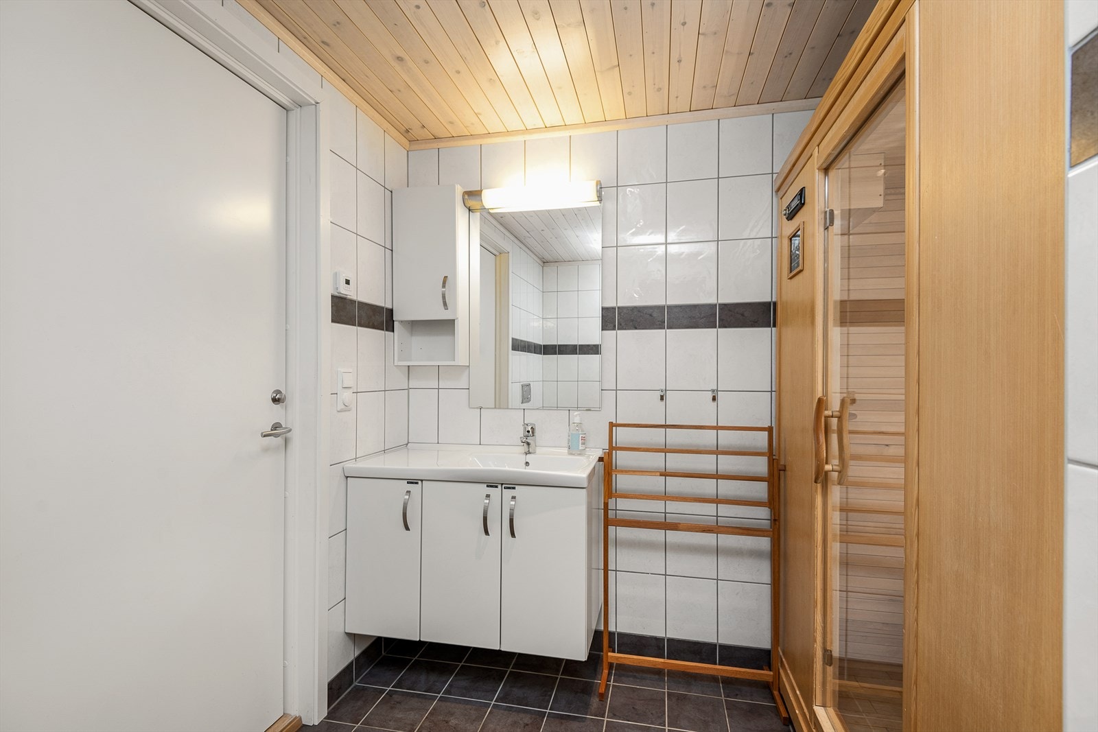 Badet i hytta er stilrent og tidløst med servantinnredning, wc, dusjnisje. Fliser på gulv og vegger. Galleribilde