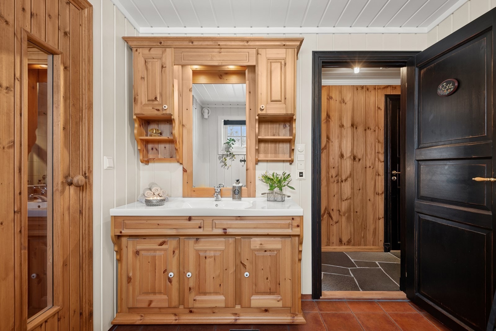 Baderommet er utstyrt med gulvstående klosett, dusj direkte på gulvet med dører i herdet glass, og en baderomsinnredning i heltre med vask i porselen. Galleribilde