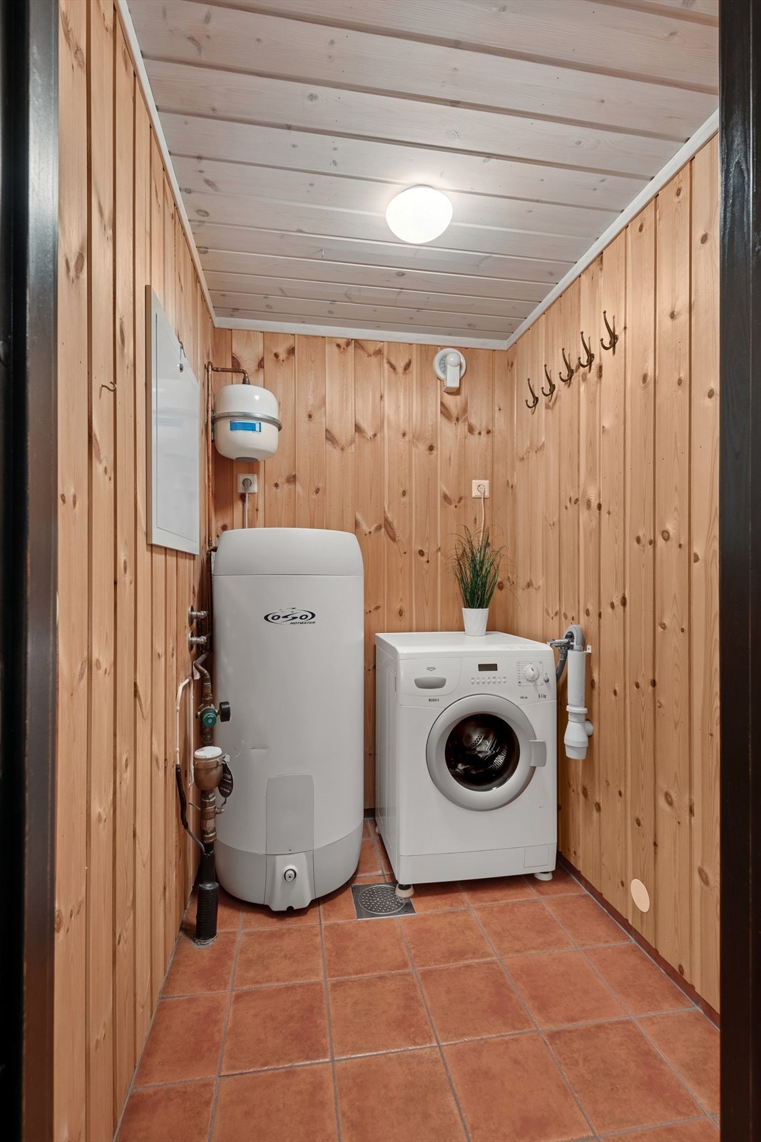 Praktisk vaskerom med gulvvarme og opplegg for vaskemaskin. Rommet er også utstyrt med varmtvannsbereder, fordelerskap og stoppekran. Galleribilde