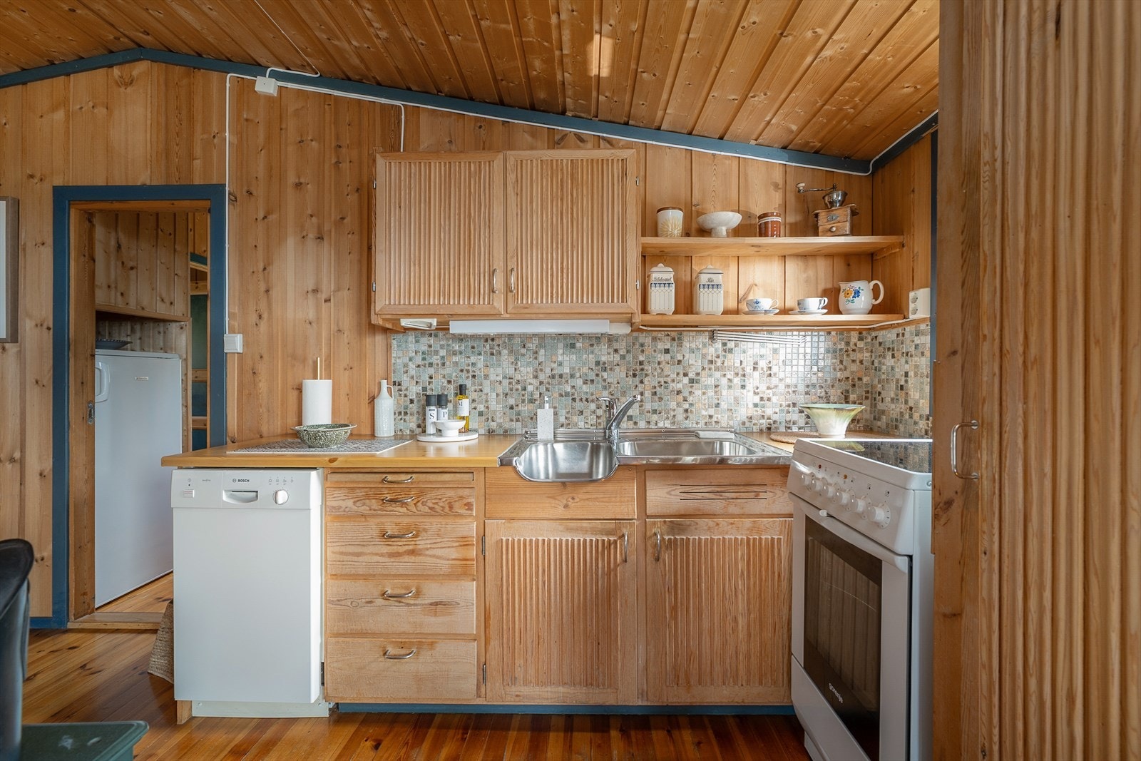 Kjøkken med trehvite profilerte fronter fra byggeår. Plass til komfyr og oppvaskmaskin. Galleribilde