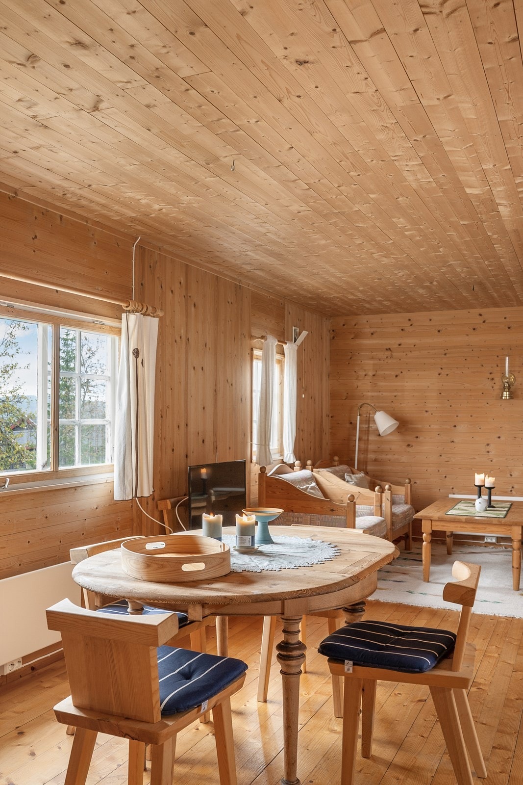 Tradisjonell stil i hytta med panelte tak og vegger. Fint lys inn i oppholdsrommet i hytta. Galleribilde