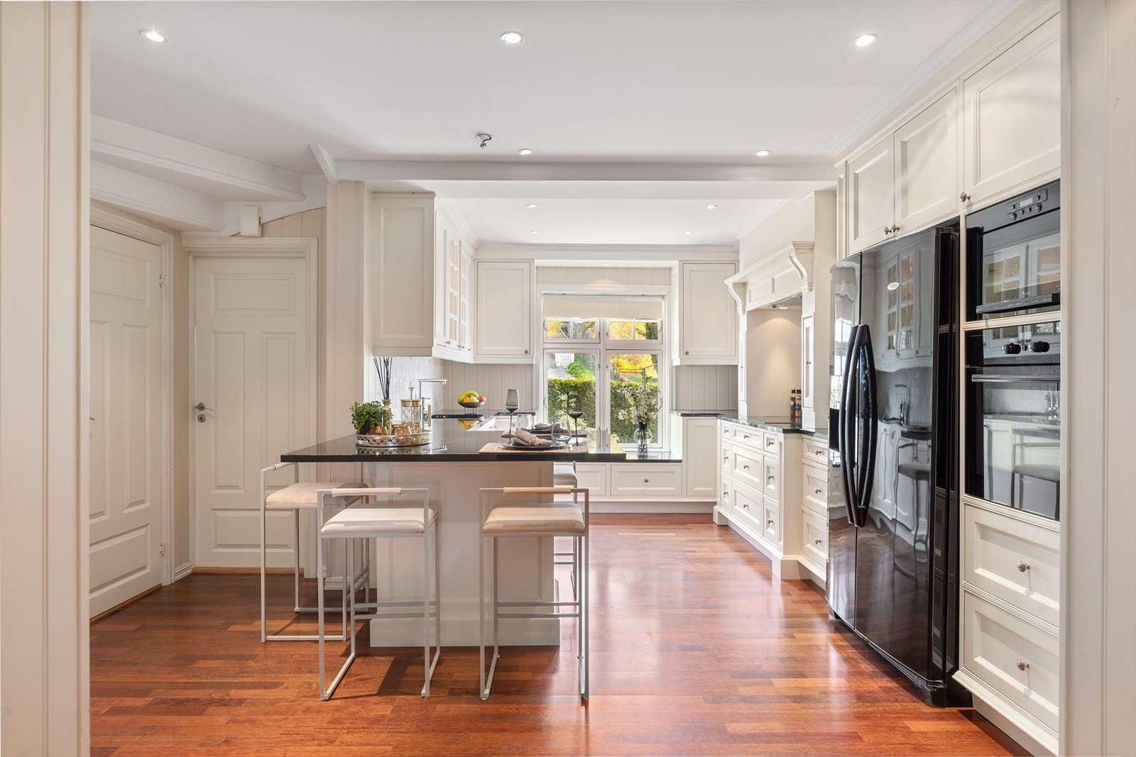 Kjøkkenet er innredet med plassbygget løsning fra J.H. Interiør, og preges av gjennomført kvalitet og elegante detaljer med en kombinasjon av profilerte fronter og vitrineskap Galleribilde