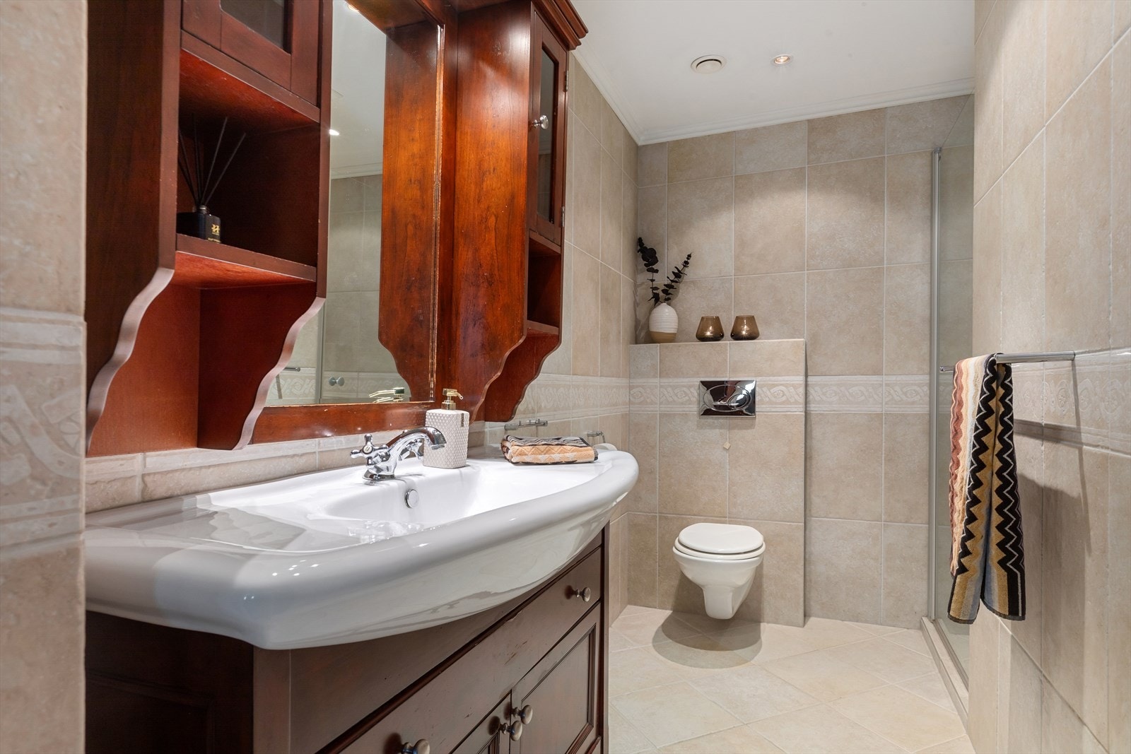 Pent flislagt bad med klassisk innredning som inkluderer vegghengt toalett og dusjnisje Galleribilde