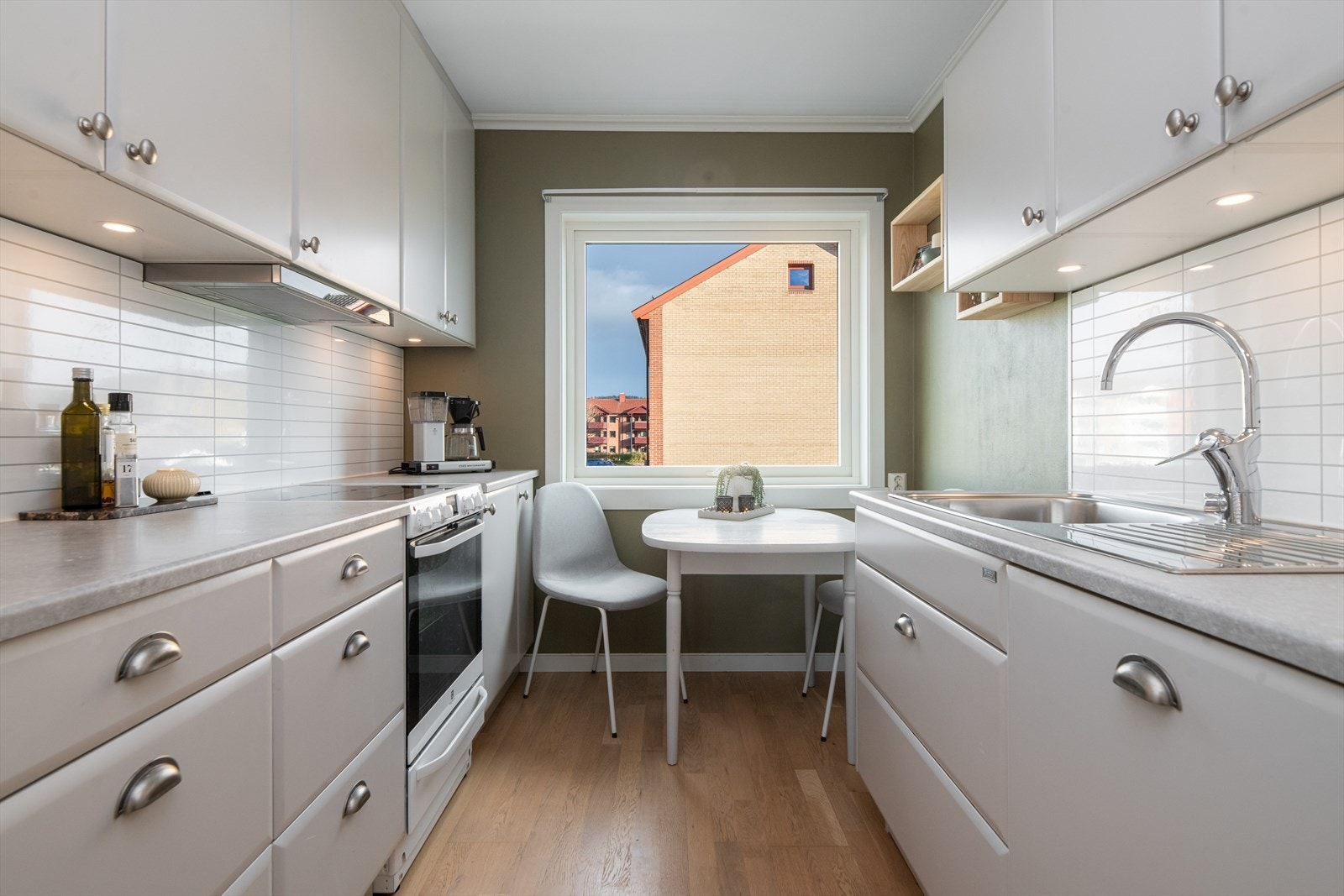 Funksjonelt og velholdt kjøkken med laminatgulv, slette fronter og benkeplater i laminat. Det er montert kjøkkenplater mellom benk og overskap for enkel rengjøring. Galleribilde