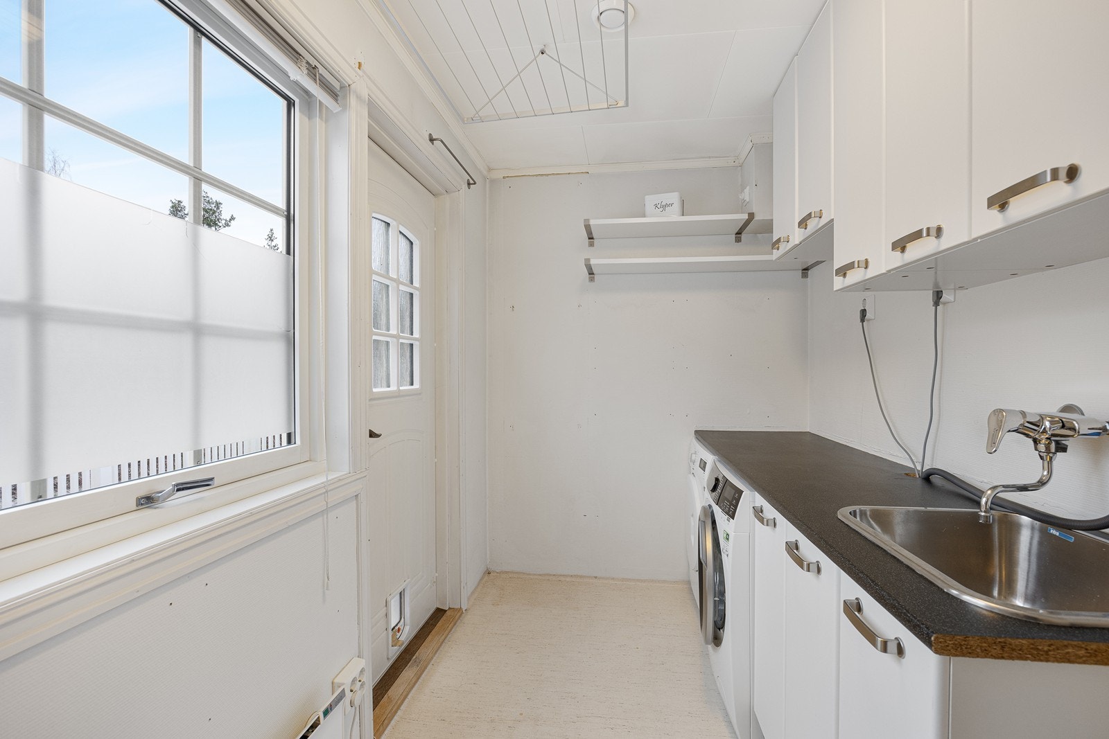 I tillegg har boligen eget vaskerom i 1. etasje, med egen utgang til terrassen. Innredningen består av praktiske benke- og overskap, og det er opplegg for vaskemaskin og tørketrommel under benkeplaten. Galleribilde