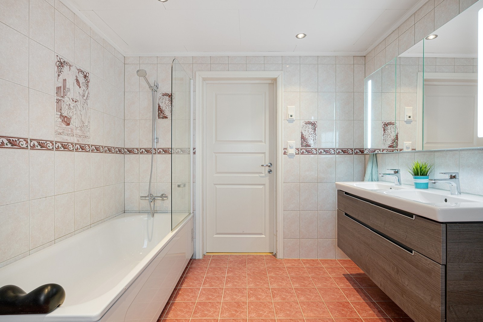 Videre har badet et nyere toalett fra 2024 og et eldre badekar med dusjløsning og vegg i herdet glass. Galleribilde