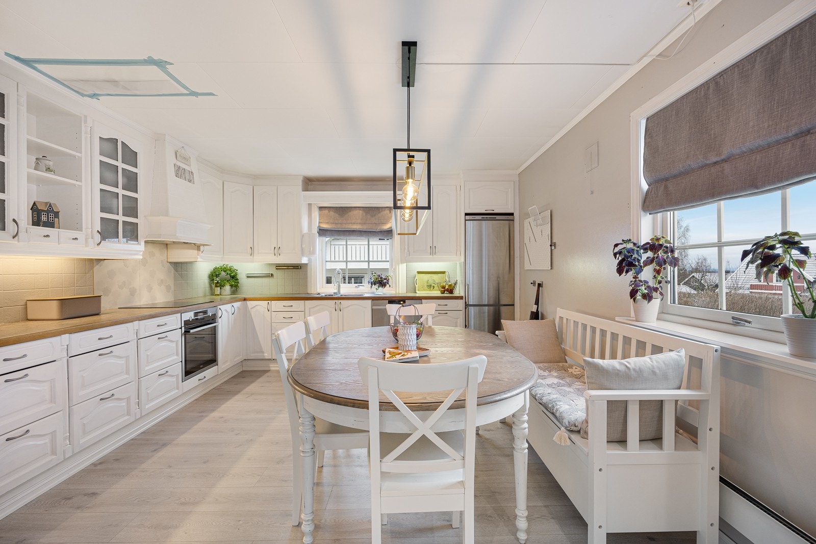 Innredningen er tidløs med hvitmalte, profilerte fronter, vitrineskap og laminatbenkeplate med dobbel oppvaskkum. Galleribilde