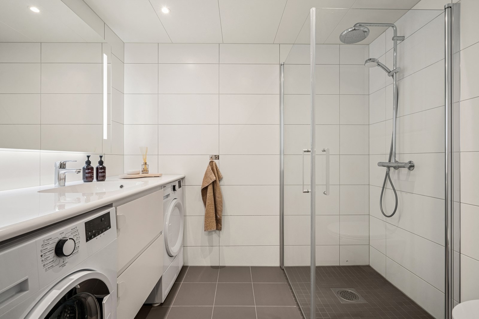 Stort og delikat bad som er flislagt med underliggende elektriske varmekabler, utstyrt med blant annet vegghengt toalett samt dusj i hjørnet bak svingbare glassvegger Galleribilde