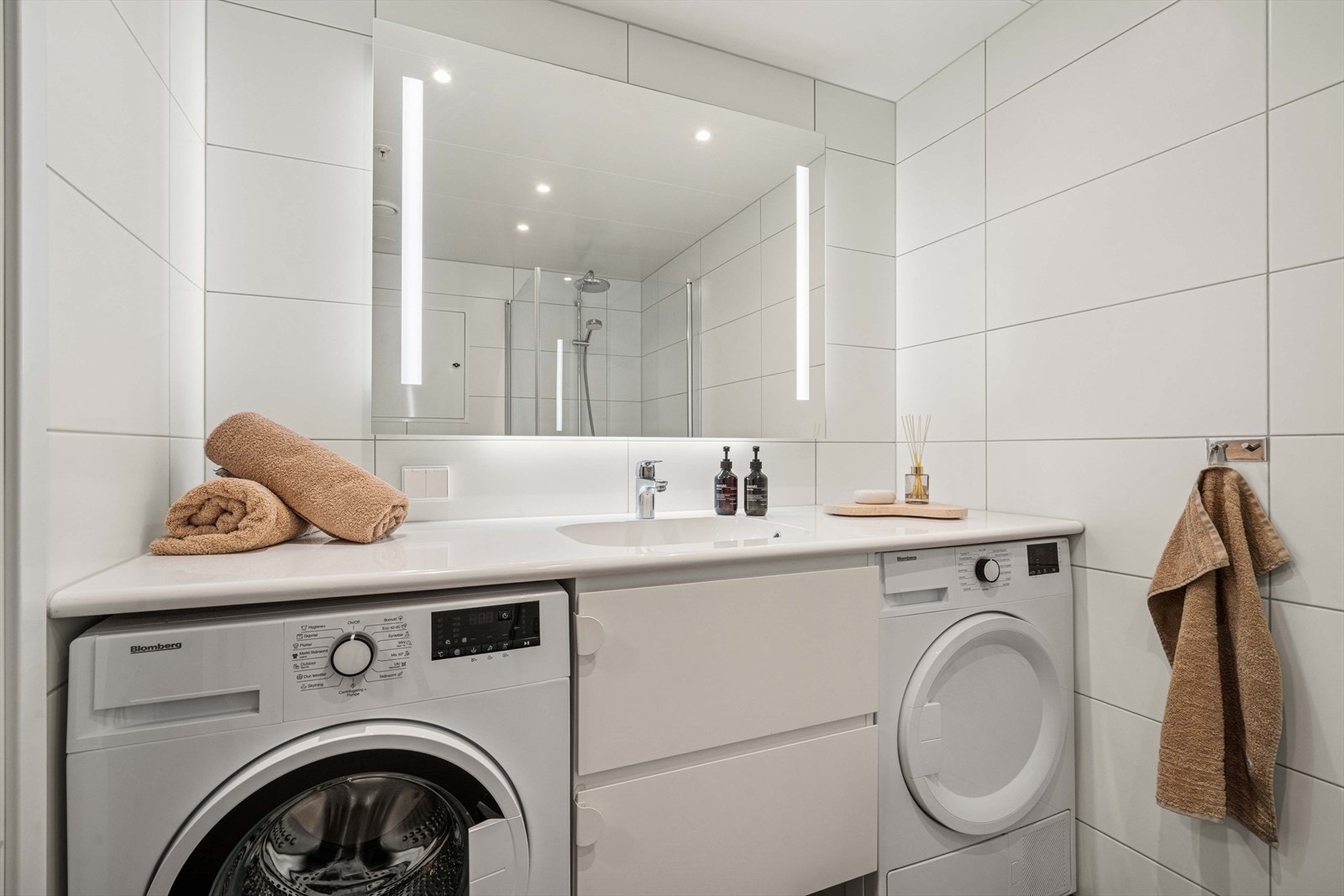 Heldekkende servant på benkeskap med fronter i glatt utførelse, speil med lys og opplegg for vaskemaskin/tørketrommel Galleribilde