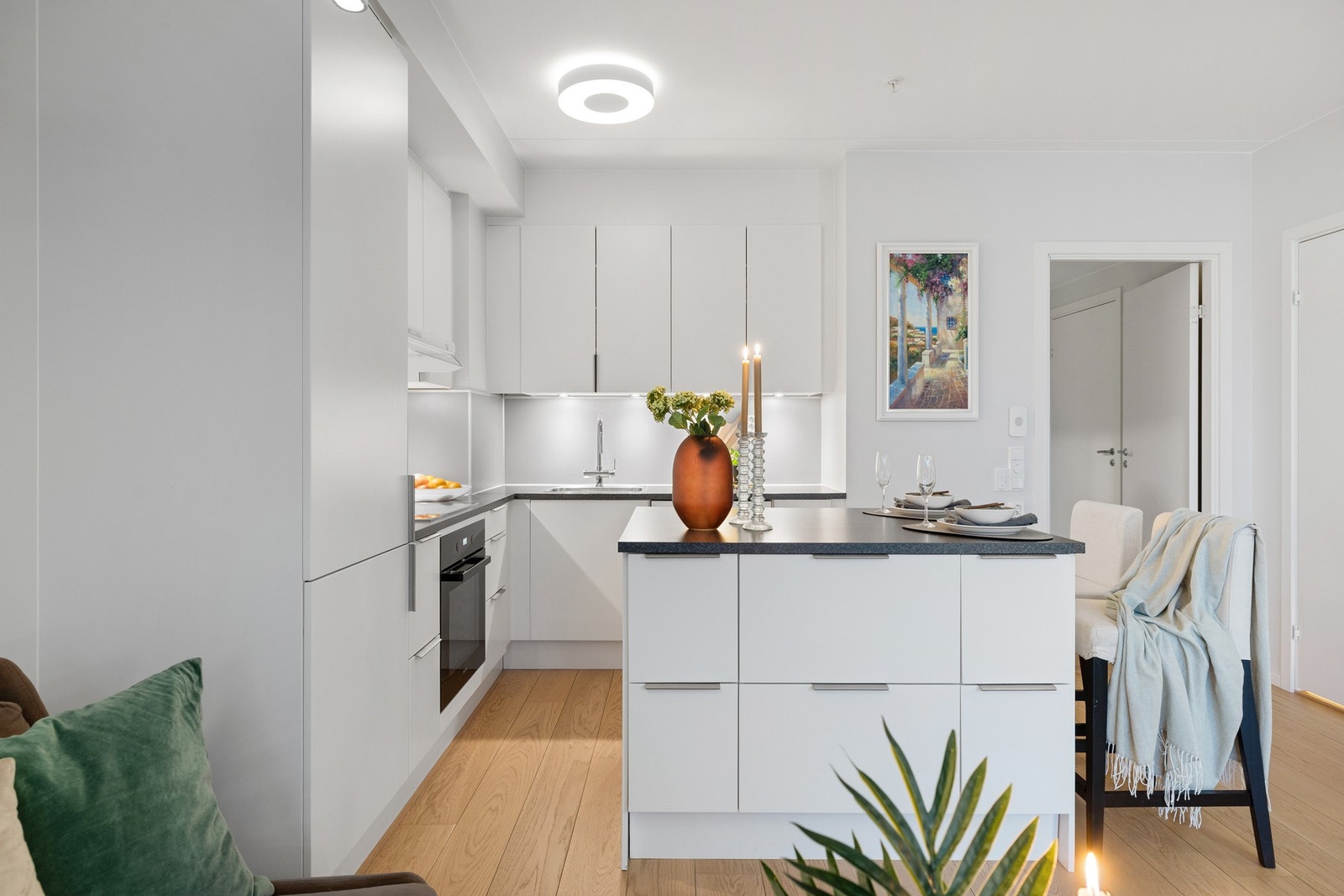 Kjøkkeninnredning er montert i L-form med hvite, glatte fronter og benkeplate i laminat Galleribilde