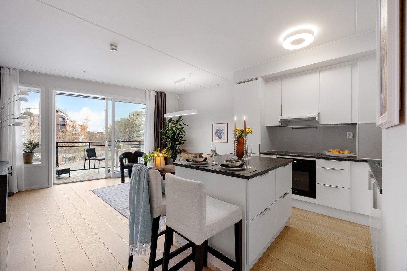 Leiligheten har en lys, trivelig stue med kjøkkeninnredning montert lengst bak i rommet Galleribilde