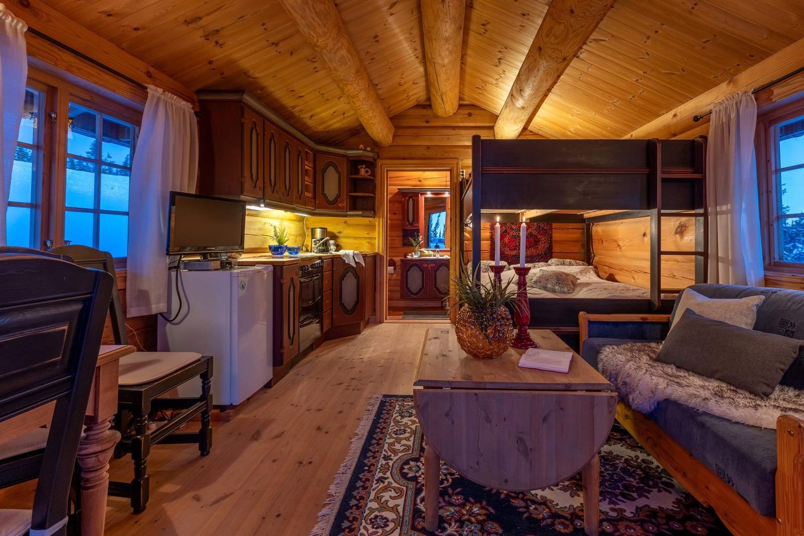 Kjøkkeninnredning fra samme leverandør, lite spisebord, sofagruppe samt familiekøyeseng med plass til 3 personer. Galleribilde