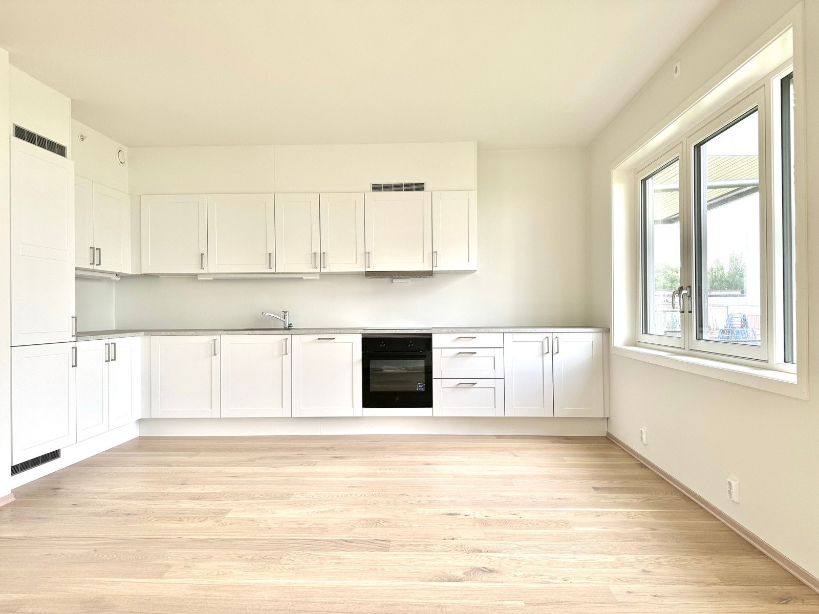 Lekkert hvitt matt Sigdal kjøkken med integrerte hvitevarer som kjøl-/frys, induksjonstopp, stekovn og oppvaskmaskin Galleribilde