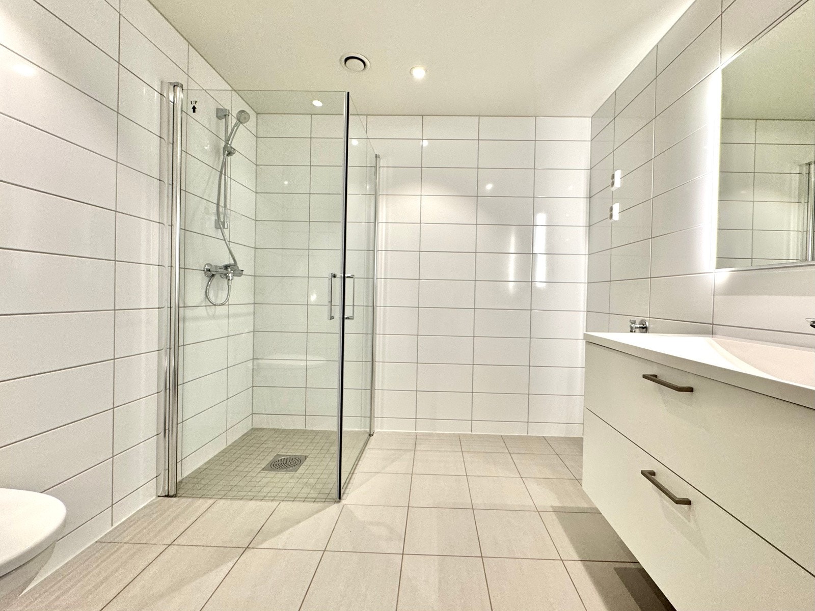 Delikat flislagt bad/wc nr 1 | down-lights | elektriske varmekabler | solid hvit matt innredning | dusjdører i glass Galleribilde
