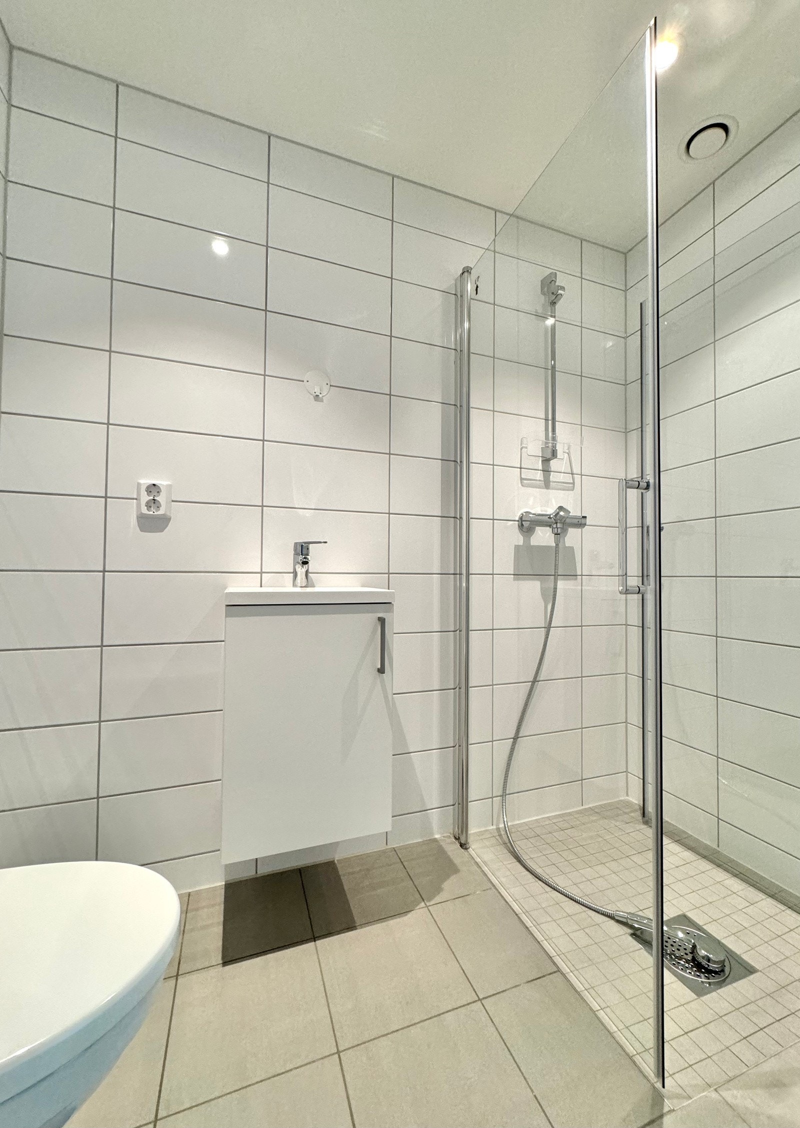 Delikat bad/wc nr 2 | dusjnisje med dusjdører i glass | vegghengt toalett | elektriske varmekabler | håndvask i innredning | down-lights Galleribilde