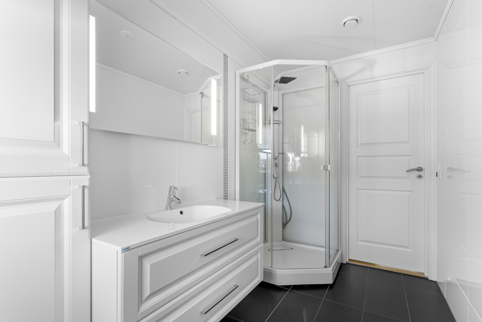 Flislagt bad med varmekabler i gulvet. Dusjkabinett, innredning med heldekkende vask, skuffer og høyskap. Galleribilde