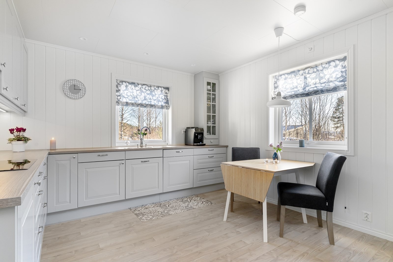 Lys grå profilert kjøkkeninnredning. Plass til spisebord og stoler. Galleribilde