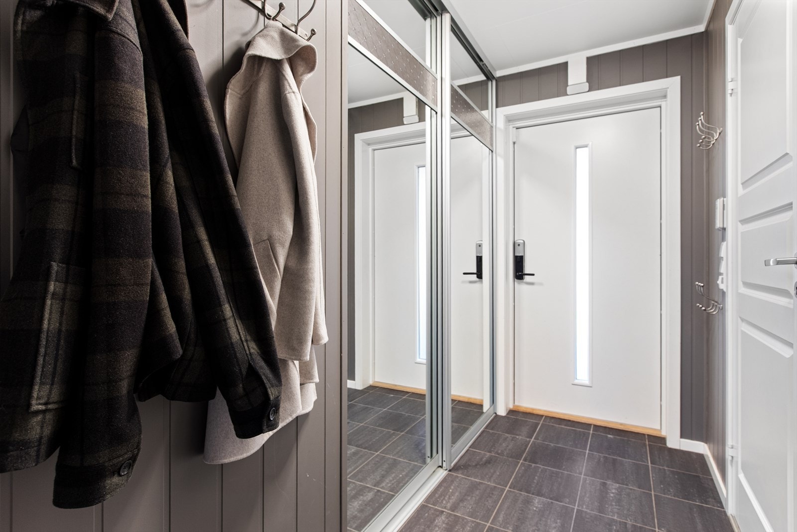 Entréen har flislagt gulv og en stor skyvedørsgarderobe med speilfronter for praktisk oppbevaring. Galleribilde