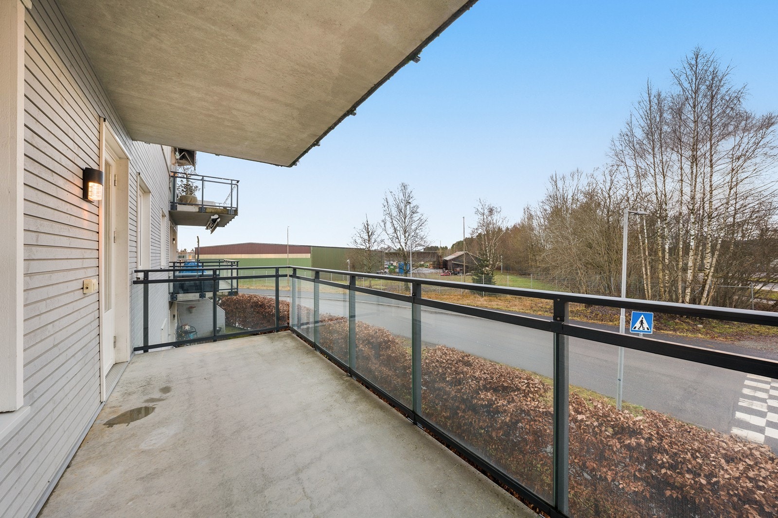 Balkongen har et solid betongdekke og rekkverk i stål og glass. Galleribilde