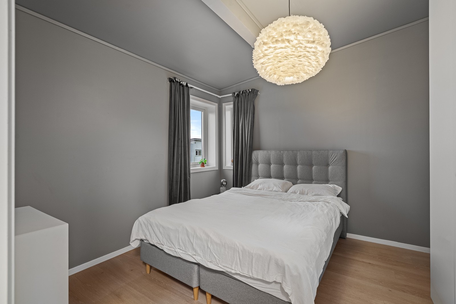 Romslig soverom med vegger og tak malt i en delikat gråfarge Galleribilde