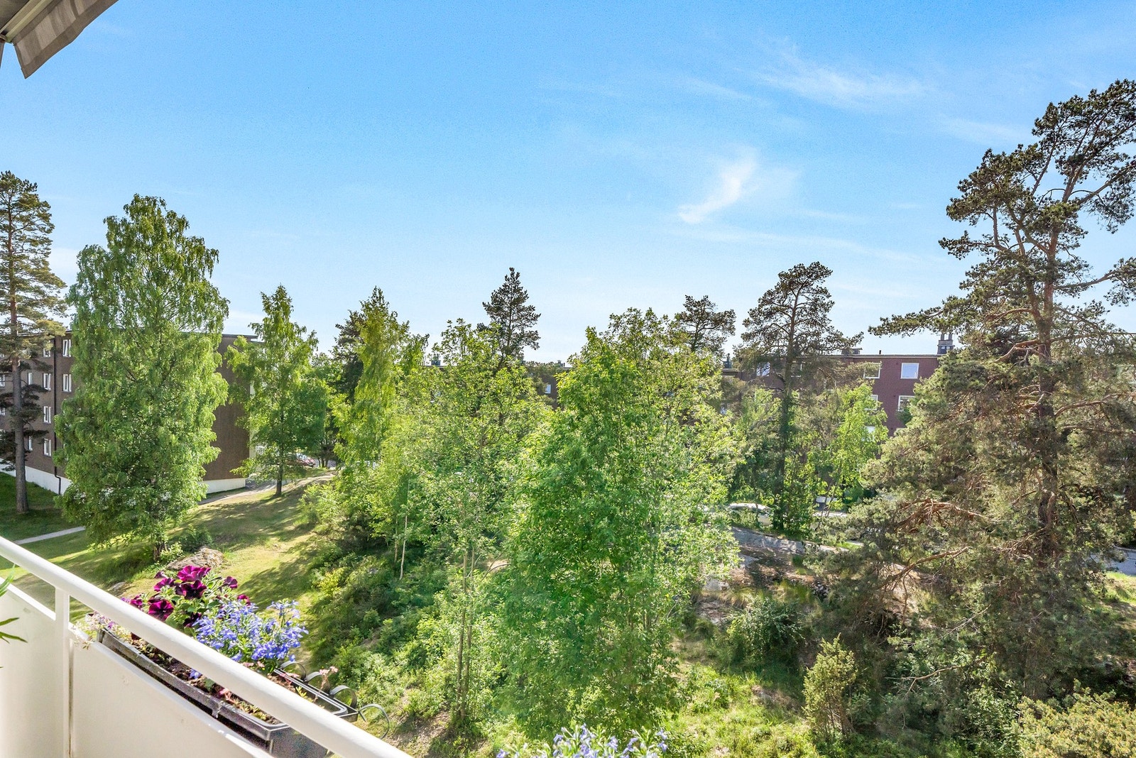 Balkongen vender ut mot et fint grøntområde. Her fra en fin sommerdag. Fra boligen er det kun en liten spasertur til Østmarka. Galleribilde