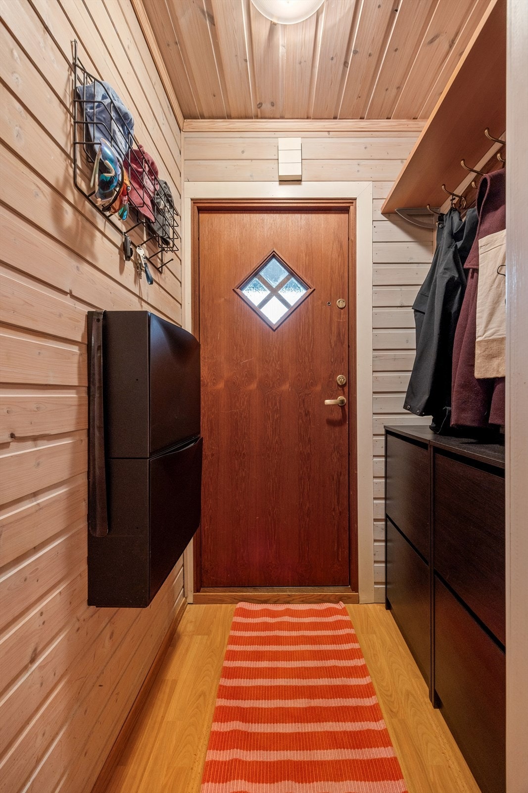 Lun og praktisk entré med god oppbevaringsplass, gjennomgående treverk og et hyggelig førsteinntrykk av leiligheten. Galleribilde