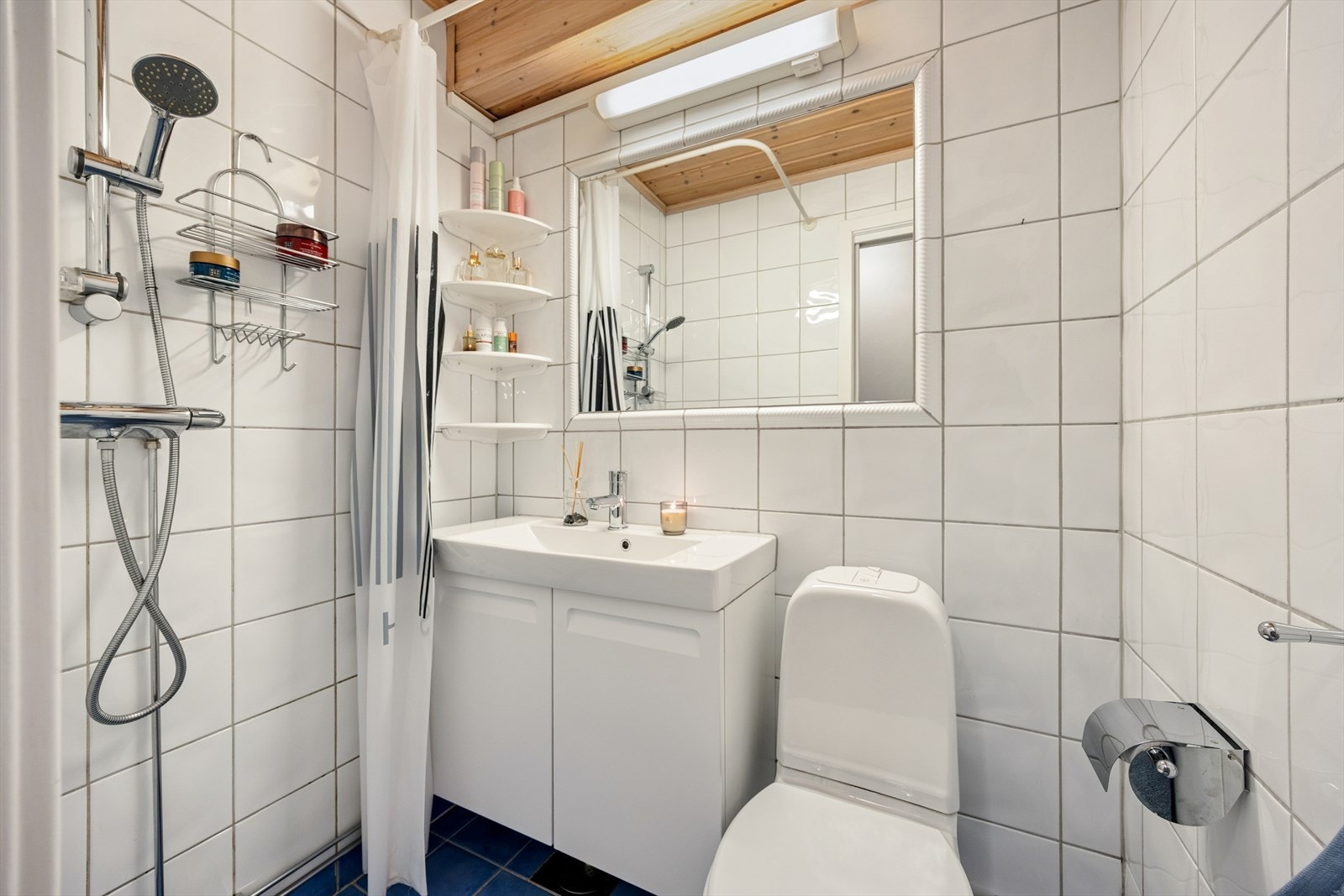 Det flislagte og funksjonelle badet er innredet med toalett, dusjhjørne og en praktisk nedfelt servant med underskap fra 2020. Galleribilde