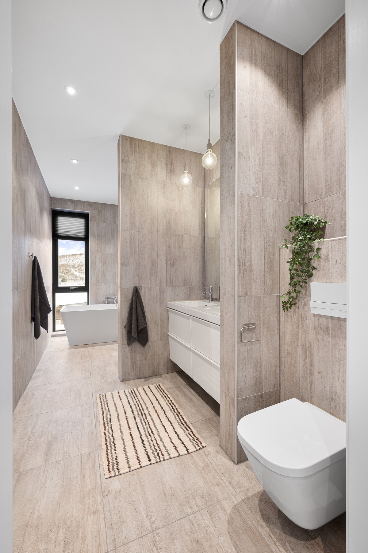 Vi begynner med bad nummer 1 - elegant inndelt i soner med korte halvvegger som gir både funksjonalitet og et stilrent uttrykk Galleribilde