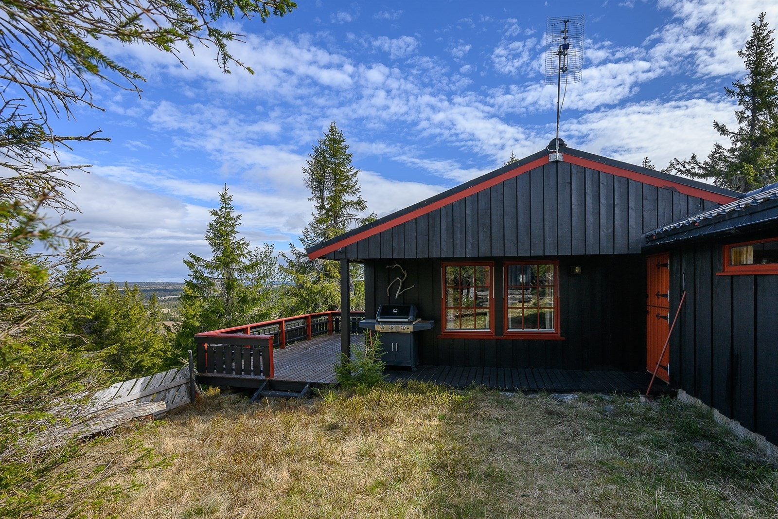 Fin og lun uteplass utenfor hytta. Det er et lite overbygg over inngangsdøra. Galleribilde