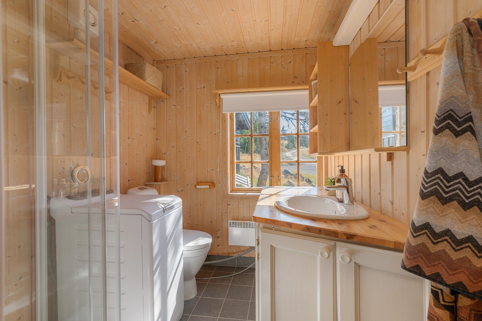 Badet dusjkabinett, WC og opplegg for vaskemaskin. Servant i innredning. Galleribilde