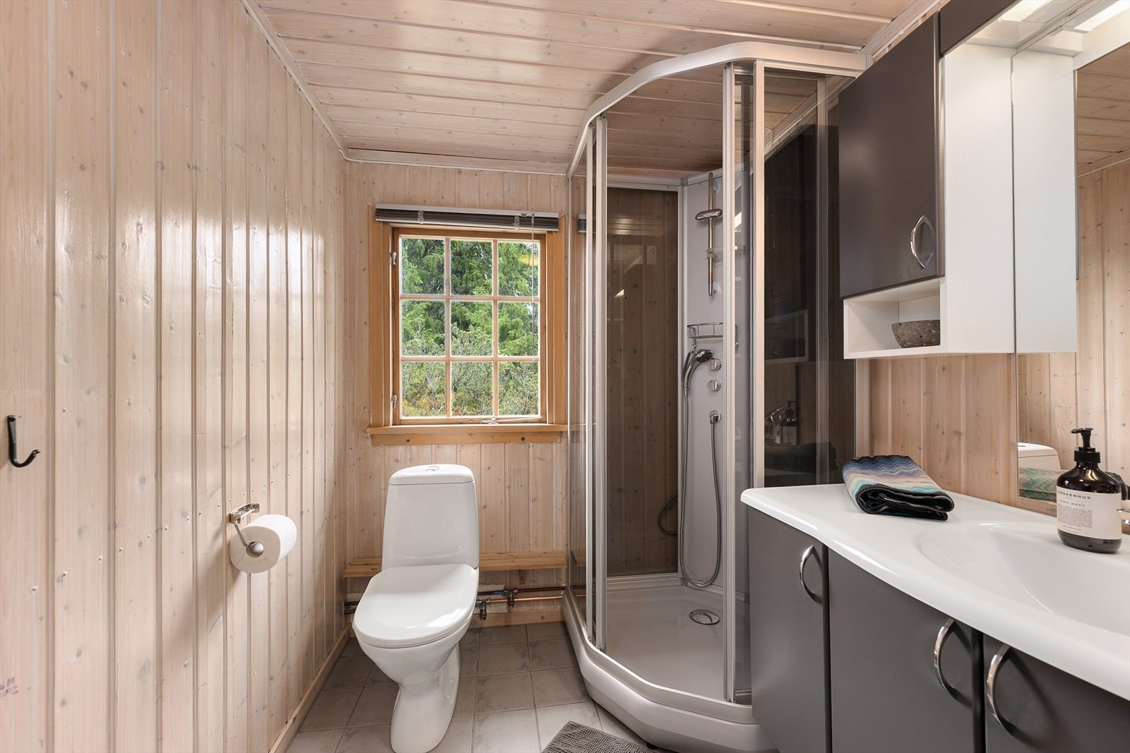 Badet har panelte tak og vegger. Fliser på gulv med varmekabler. Galleribilde