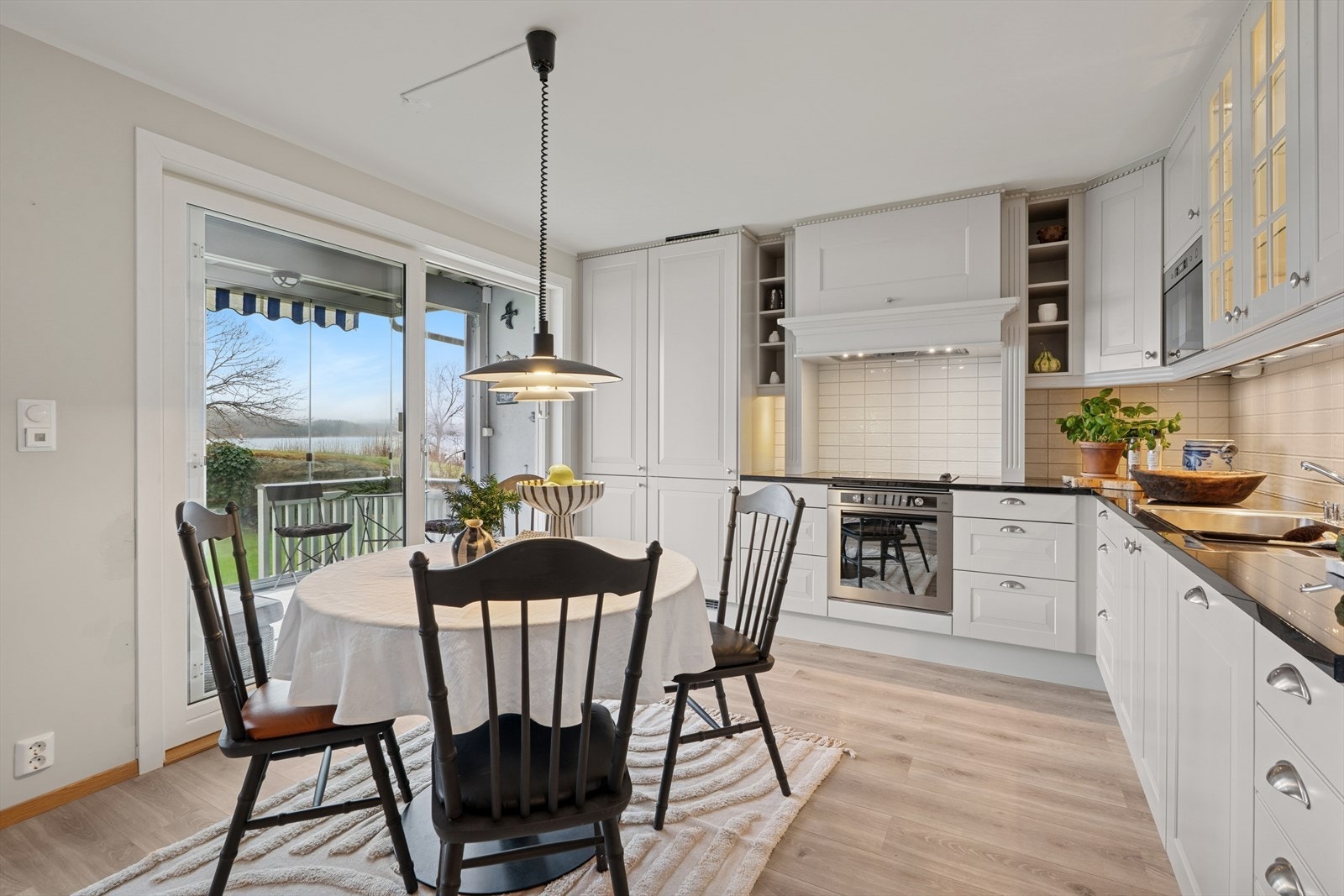 Norema innredning med profilerte fronter, enkelte overskap med glass og sprosser, og en stilfull benkeplate i stein som gir et tidløst og elegant uttrykk Galleribilde