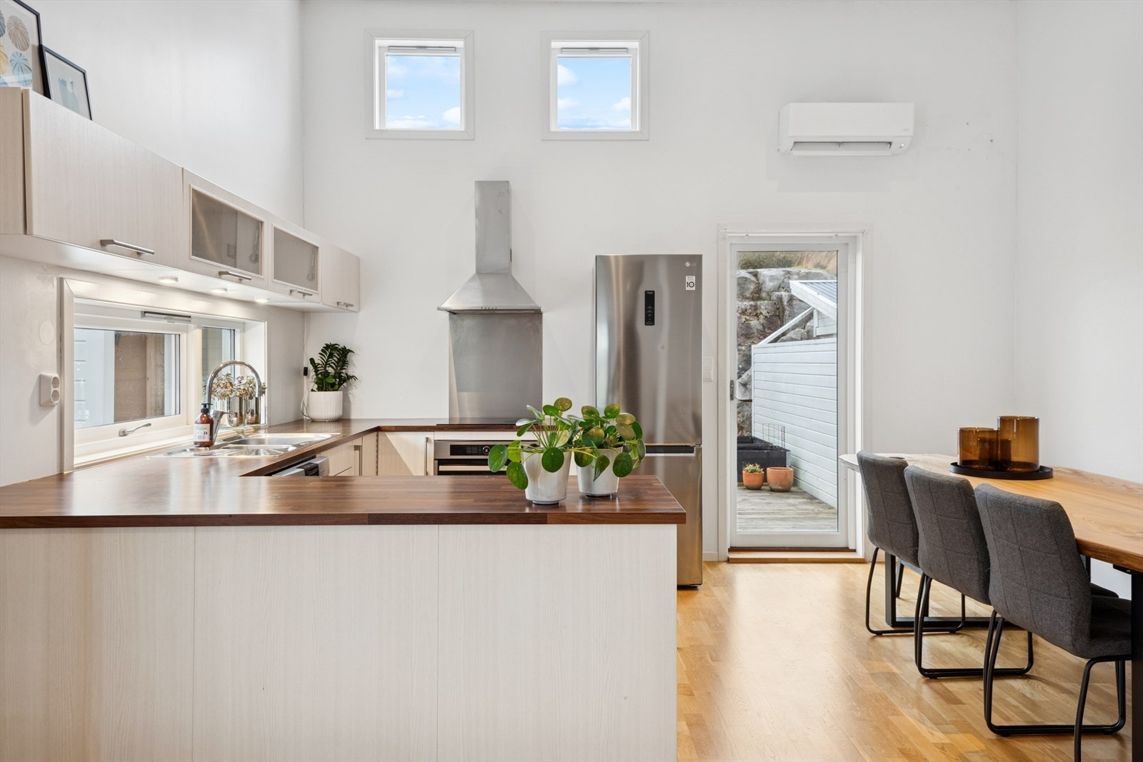 Integrerte hvitevarer og stålplate bak koketopp gir et praktisk kjøkkenområde. Galleribilde